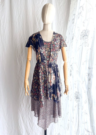 1970s short-sleeve tiered floral dress with a navy blue base with and a multicolor floral pattern 