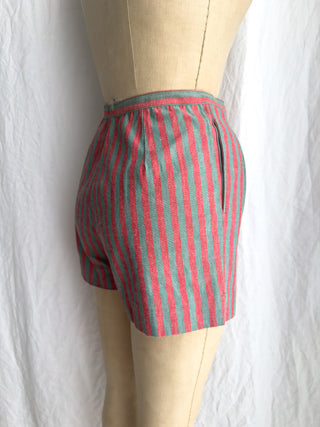 Side view of red and teal striped shorts displayed on a beige mannequin torso against a white fabric backdrop.