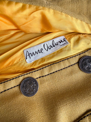 Close-up of a yellow satin interior lining with a visible Anne Valone Paris label and dark buttons on a textured linen fabric exterior.