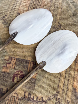 Close up view of the back of two oval white mother-of-pearl spoons
